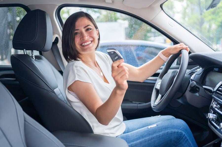 Woman in white shirt holding car keys she got from an auto loan harlingen credit union.