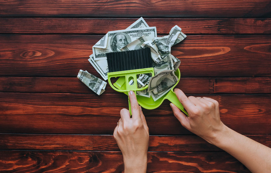 Female hands hold a brush and scoop and remove dollar bills from the wooden table at the bank Brownsville and local federal credit union.