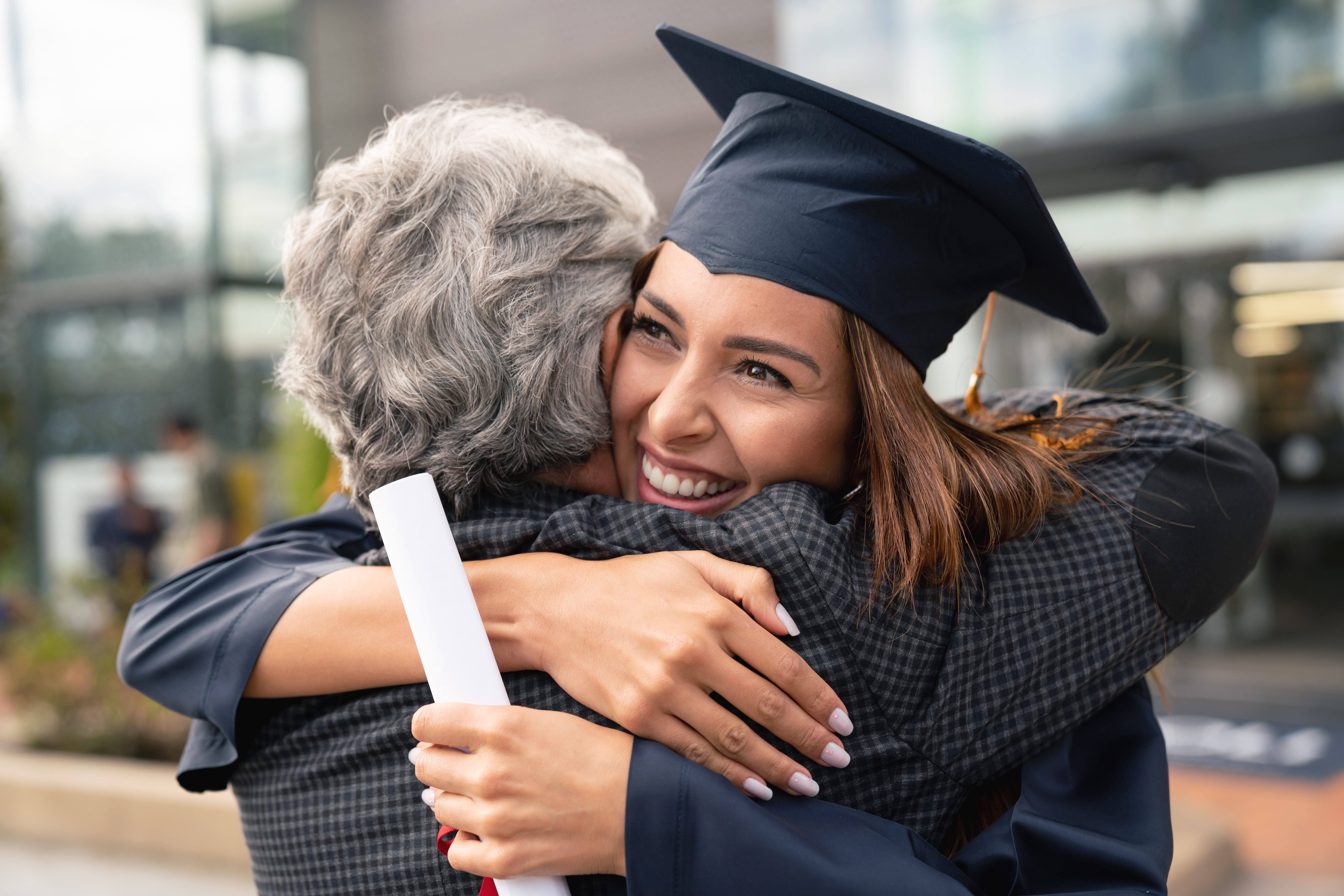 Happy student hugging her father and celebrating her graduation at a local federal credit union in Harlingen